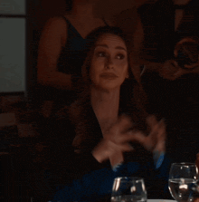 a woman sitting at a table with a glass of wine