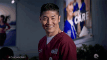 a man in a chicago medical center scrub smiles in front of a sign that says " the care "