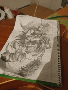 a spiral notebook with a drawing of a demon with horns