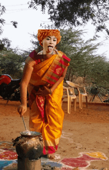 a woman in a yellow and red saree is cooking