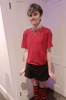 a young man wearing a red shirt and black skirt