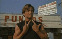 a man giving the middle finger in front of a tortilleria sign