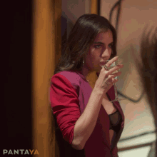 a woman in a red jacket drinking a glass of wine with pantaya written on the bottom