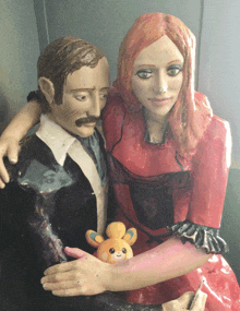 a statue of a man and a woman with a stuffed animal