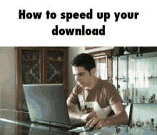 a man is sitting at a table using a laptop with the words " how to speed up your download " above him