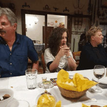 a man and two women sit at a table with a sign on the wall that says ' agriturismo '