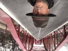 a man wearing a hat is upside down on a red bridge