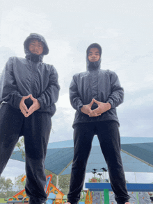 two men wearing hooded jackets pose for a photo