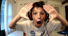 a young boy wearing headphones and a shirt with the number 9 on it is making a surprised face