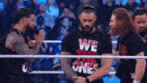 a man in a we the ones shirt is standing in a wrestling ring