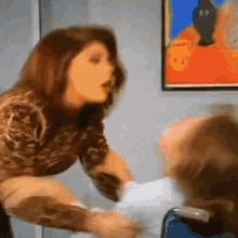 a woman is holding a child in a wheelchair in front of a painting on the wall