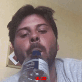 a man with a beard is drinking from a bottle with a label that says ul ccf