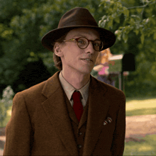 a man wearing a hat and glasses looks at the camera