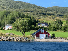 a red barn sits near a body of water