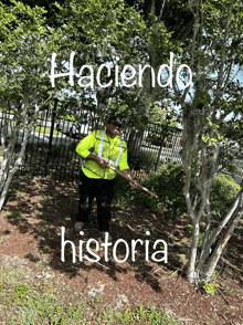 a man in a yellow vest is standing next to a tree with the words haciendo historia written on it