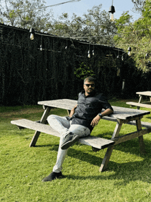 a man is sitting on a wooden picnic table