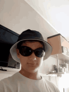 a young boy wearing a hat and sunglasses poses for a photo