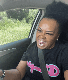 a woman wearing a black shirt with the letter d on it making a funny face