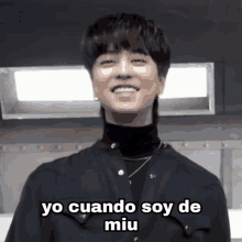 a young man wearing a black shirt and a turtleneck smiles and says yo cuando soy de miu .