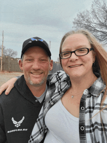 a man and woman posing for a picture with the man wearing a shirt that says air force on it