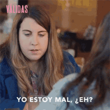 a woman in a blue coat is talking to another woman and says yo estoy mal eh ?