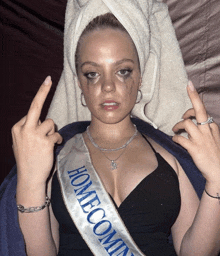 a woman wearing a sash that says homecoming giving the middle finger