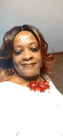 a woman wearing a red necklace and earrings smiles for the camera