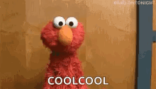 elmo from sesame street is standing next to a wall and saying `` cool cool '' .