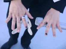 a close up of a person 's hands with rings on them