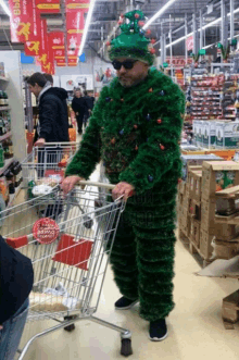 a man dressed as a christmas tree is pushing a shopping cart