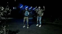 a couple of men are dancing in the dark with their arms in the air