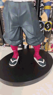 a figurine of a man wearing flip flops is standing on a black base