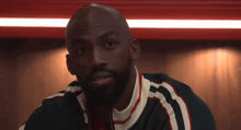 a man with a beard is wearing a black jacket with red and white stripes