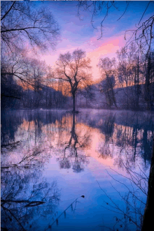 a sunset over a lake with trees reflected in it