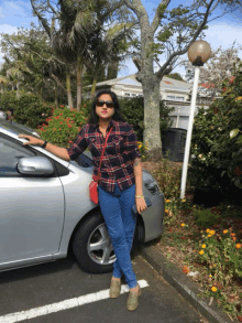 a woman wearing sunglasses stands next to a car