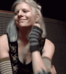 a woman with blonde hair is wearing striped gloves and a black tank top .