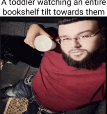 a toddler watching an entire bookshelf tilt towards them with a man holding a cup