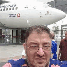 a man is taking a selfie in front of a plane .