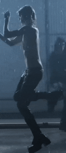 a shirtless man is dancing in a dark room