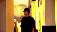 a man wearing a black shirt and a black hat is standing in a hallway