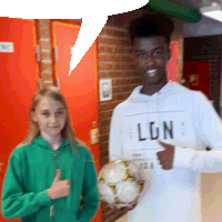 a boy wearing a lion sweatshirt holds a soccer ball next to a girl