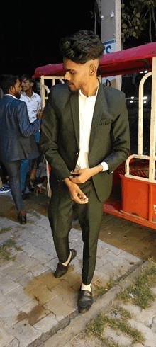 a man in a green suit is standing in front of a red rickshaw