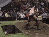a wrestler wearing a black shorts with the word gear on it stands in the dirt