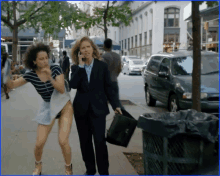 a woman in a suit is talking on a cell phone while a woman in shorts runs down the street