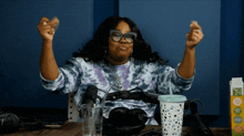a woman sitting at a table with her arms in the air next to a carton of tropicana