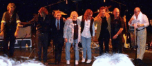 a group of people standing on a stage with a drum set