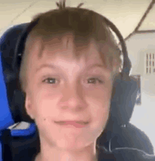 a young boy wearing headphones is sitting in a blue chair and smiling .