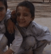 two young boys are posing for a picture while kneeling down .