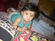 a baby with a black spot on her forehead is laying down on a bed