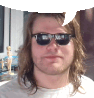 a man with long hair wearing sunglasses and a white shirt